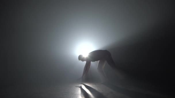 Człowiek praktykujący Capoeira w ciemności przeciwko reflektorom w ciemnym studiu. — Wideo stockowe