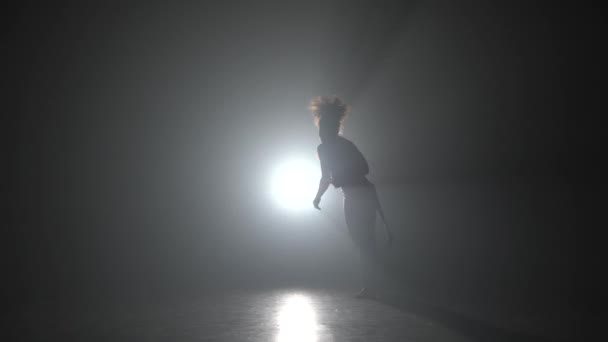 Curl fêmea praticando capoeira na escuridão contra holofotes de luz no estúdio . — Vídeo de Stock