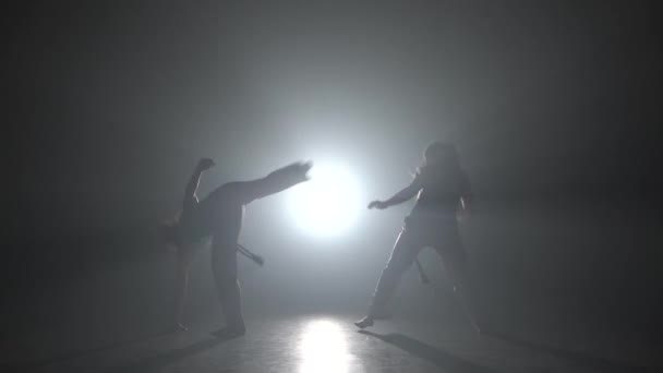 スタジオでスポットライトに対して暗闇の中でカポエイラを練習する強い女性. — ストック動画