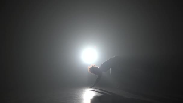 スタジオでスポットライトに対して暗闇の中でカポエイラを練習する運動少女. — ストック動画