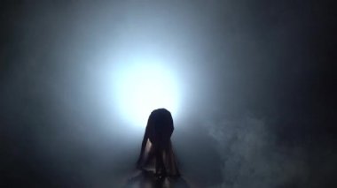 Karanlık stüdyoda tefekme performans gösteren büyüleyici bir kadın hareket.
