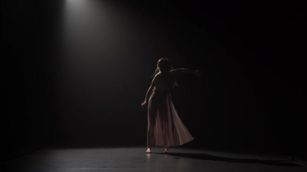 Motion of a girl practicing contemp in dark studio. — Stock Video