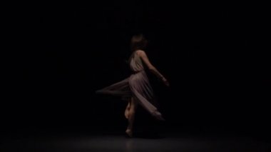 Dansçı kadın stüdyoda alacakaranlıkte tefekkme performans. Yavaş çekim