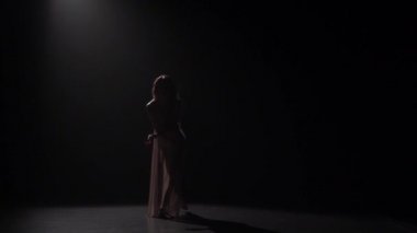 Karanlıkta stüdyoda uzun saçlı dans eden kadının yavaş hareketi