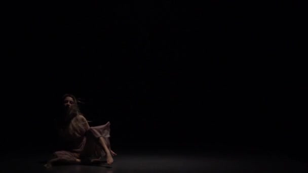 Charmante Performerin tanzt Wettstreit in der Dämmerung vor schwarzem Hintergrund. Zeitlupe — Stockvideo