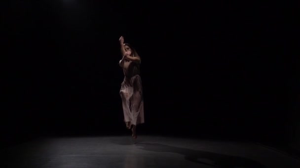 Kvinna som utför Dans elementen mot svart bakgrund i Spotlight. — Stockvideo