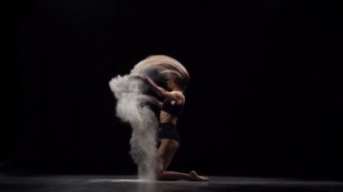 Havada toz parçacıkları atan profesyonel dansçı yavaş hareket.