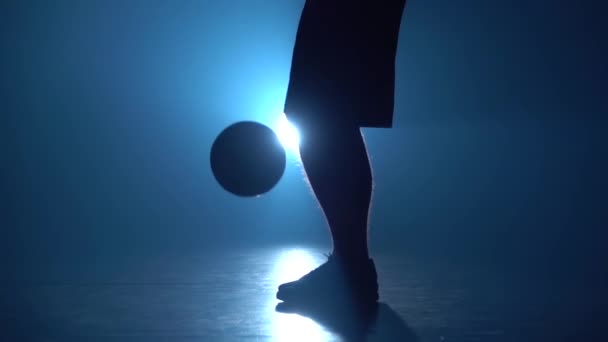 Estilo libre de fútbol. Primer plano de las piernas de fútbol freestyler relleno bola contra proyector azul en el estudio. Movimiento lento — Vídeo de stock