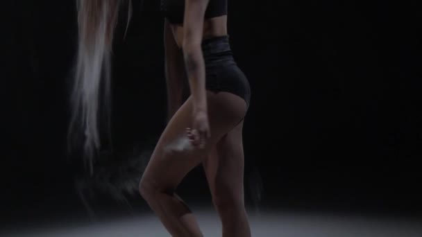 理想的な体を持つ女の子は、黒の背景にスタジオでほこりを投げる。スローモーション — ストック動画
