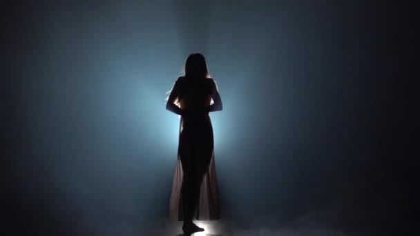 Spot ışığına karşı karanlık stüdyoda tefekme performans gösteren kadın yavaş hareket. — Stok video