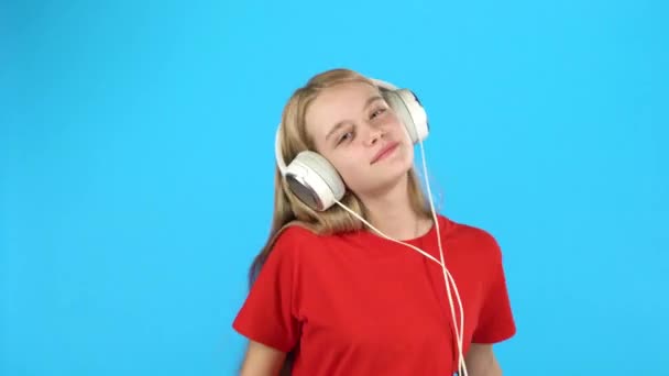 Chica escuchando música en grandes auriculares blancos, cantando y bailando — Vídeo de stock