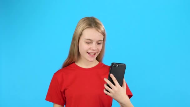 Jolie petite fille tenant un téléphone et parlant avec quelqu'un par appel vidéo — Video