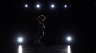 Esmer kadın stüdyoda spot karşı karanlıkta capoeira pratik.