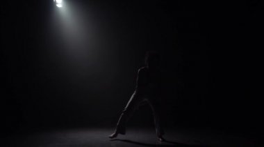 Stüdyoda spot karşı karanlıkta capoeira pratik yakışıklı kadın.
