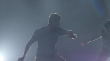 Yakın çekim adamlar stüdyoda spot karşı karanlıkta capoeira pratik, yavaş hareket