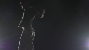 Stüdyoda spot ışıkları nda capoeira uygulayan adam. Yakın çekim yavaş çekim.