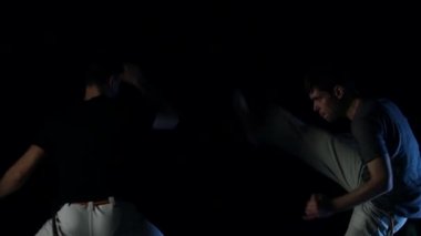 Kaslı erkekler stüdyoda karanlıkta capoeira pratik. Yakın çekim yavaş çekim