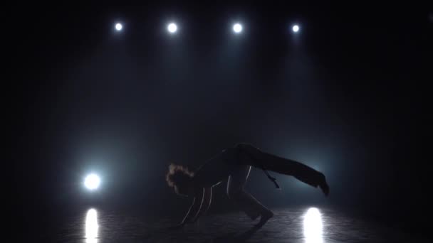 Capoeira dans l'obscurité contre les projecteurs en studio. Mouvement lent . — Video