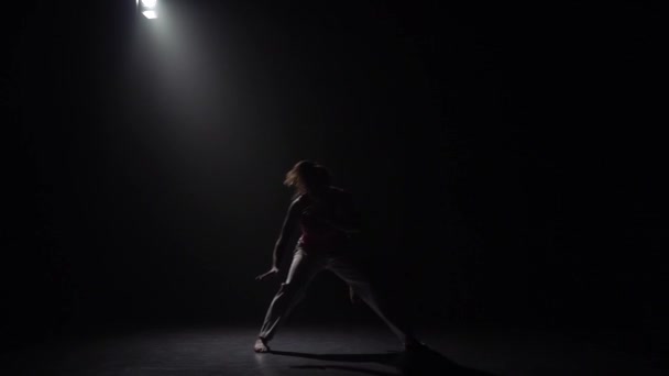 スタジオでスポットライトの下で暗闇の中でカポエイラを練習スローモーション女性. — ストック動画