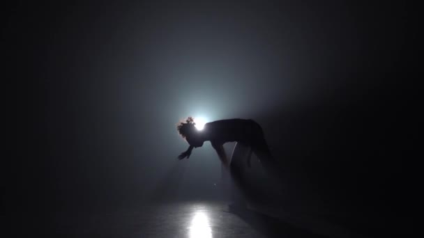 Slow motion. Capoeira. Silhuett av lockig flicka i mörker mot ljus Spotlight. — Stockvideo