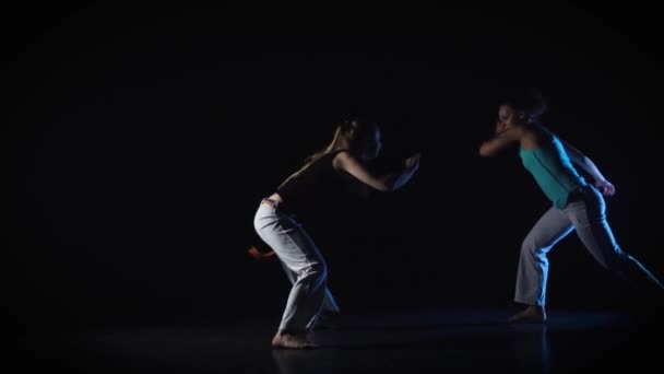 Twee vrouwtjes zijn het uitvoeren van een complex van krijgskunst van capoeira. Slow Motion — Stockvideo