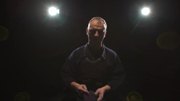Kendo Warrior sätter på hjälm på bakgrunds strålkastare — Stockvideo
