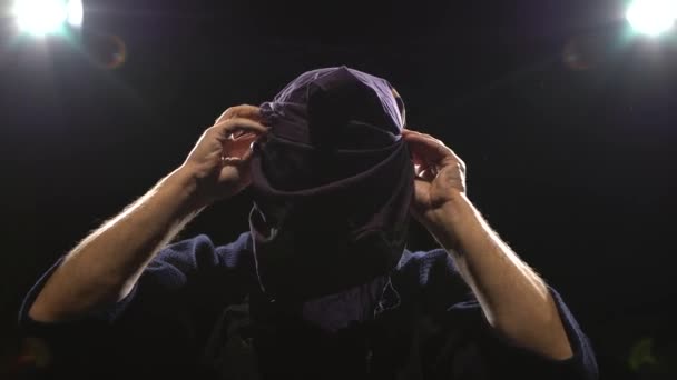 Close-up of kendo warrior is putting on helmet at background spotlights. Dolly shot — Stock Video