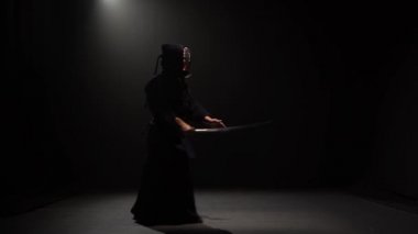 Kendo savaşçı spot altında karanlık stüdyoda Katana kılıç ile dövüş sanatı performans.