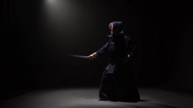 Kendo savaşçı spot altında karanlık stüdyoda Katana kılıç ile dövüş sanatı performans.