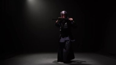 Kendo savaşçı spot altında karanlık stüdyoda Katana kılıç ile dövüş sanatı performans.