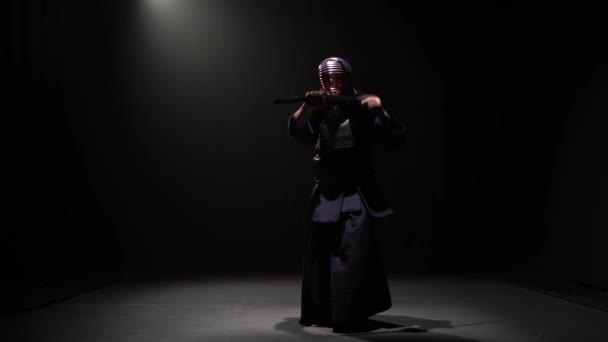 Luchador Kendo realizando arte marcial con espada Katana en estudio oscuro bajo foco . — Vídeos de Stock