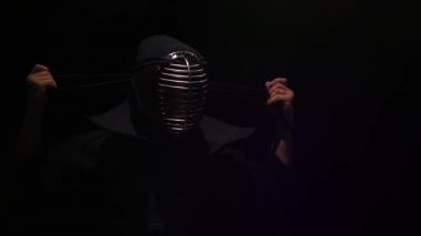 Kendo ustası miğferindeki bağcıkları bağlıyor, yavaş çekim.