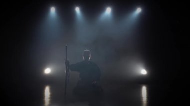 Kendo eğitmeni Katana kılıcını çıkarıp yere koyuyor. Yavaş çekim.