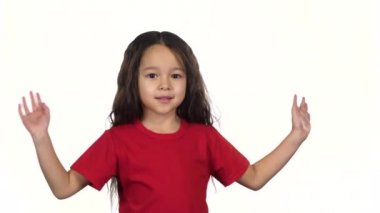 Küçük koyu saçlı kız elleri beyaz arka planda sallanıyor. Yavaş çekim