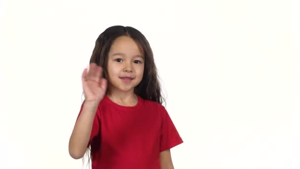 Маленький темноволосый ребенок машет рукой на белом фоне. Медленное движение — стоковое видео
