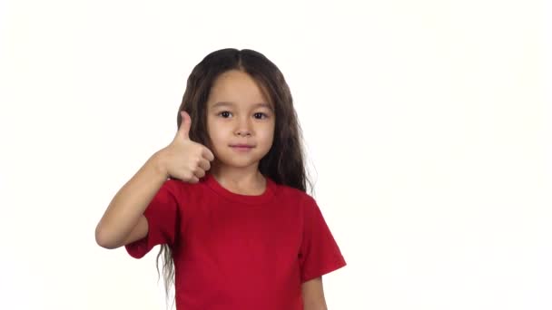 Retrato garoto inteligente mostrando os polegares acima de suas mãos no fundo branco. Movimento lento — Vídeo de Stock