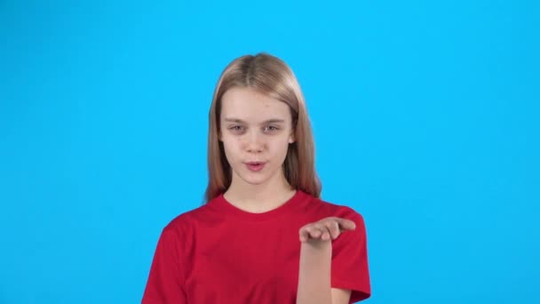Kleine vrouwelijke poseren en klappen kus op blauwe achtergrond. Slow Motion — Stockvideo