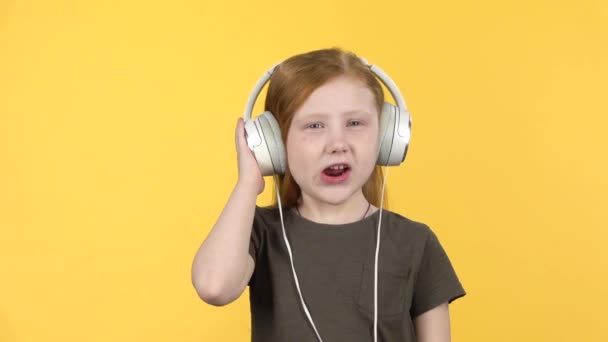 Baby listening to music in big white headphones, singing and dancing. Slow motion — Stock Video