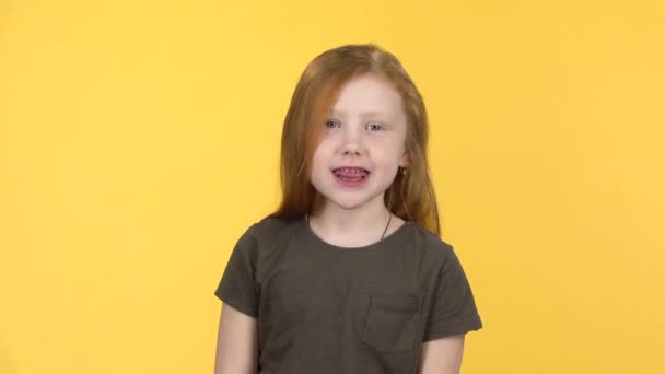 Engraçado menina ruiva sorri para a câmera e mostra a língua. Movimento lento — Vídeo de Stock
