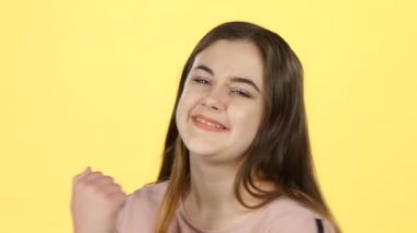 Clous-up genç kadın sarı arka plan ellerini alkışlar. Yavaş çekim
