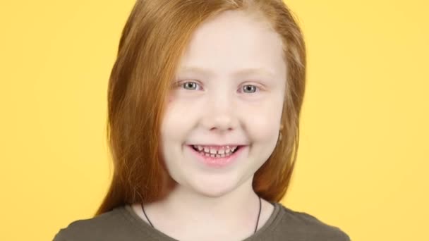 클로즈업 빨간 머리의 아이가 웃고 노란색 배경에 카메라를 본다. 슬로우 모션 — 비디오