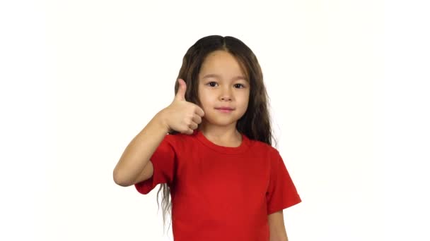 Retrato inteligente niña mostrando pulgares hacia arriba sus manos sobre fondo blanco — Vídeo de stock