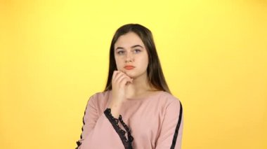 Genç kız sarı arka planda duygu gösteren