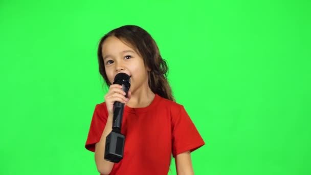 Dark-haired baby with microphone on green background — Stock Video