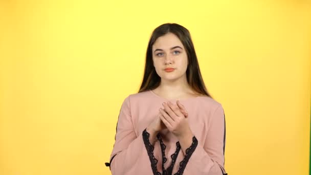 Mujer bonita posando felizmente sobre fondo amarillo. 4k — Vídeos de Stock