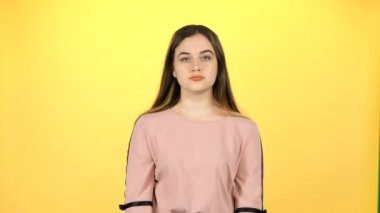 Genç güzel kız sarı arka plan üzerinde şaşırtıcı poz