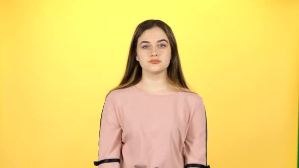 黄色の背景に驚くほどポーズをとる若い美しい女の子 — ストック動画