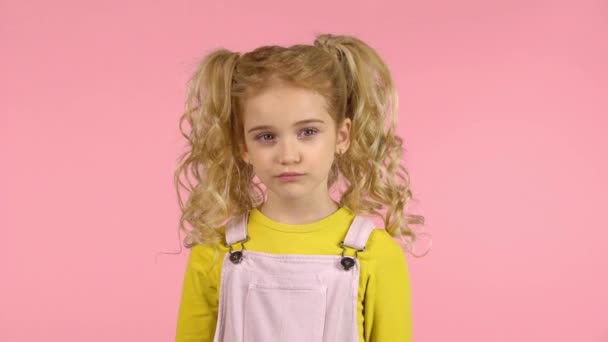 Blond barn pursing hennes läppar, med tankeväckande lekfulla ansikte vänder huvudet och rullande hennes ögon — Stockvideo