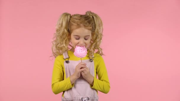 Όμορφο θηλυκό παιδί τρώει μια καραμέλα στο ραβδί — Αρχείο Βίντεο