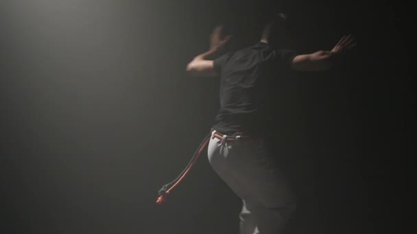 Man beoefenen Capoeira in Ray van Spotlight in Studio. Close-up slow motion. — Stockvideo